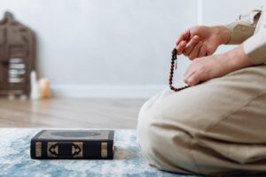 Muslim on Prayer Mat with Quran and Rosary