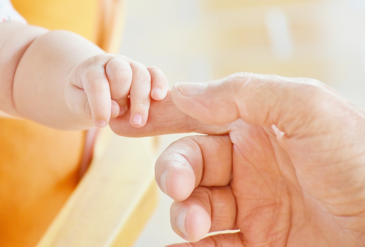 Adult holding baby hand