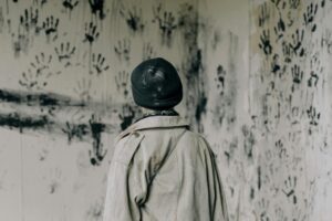 person look at wall with black hand prints
