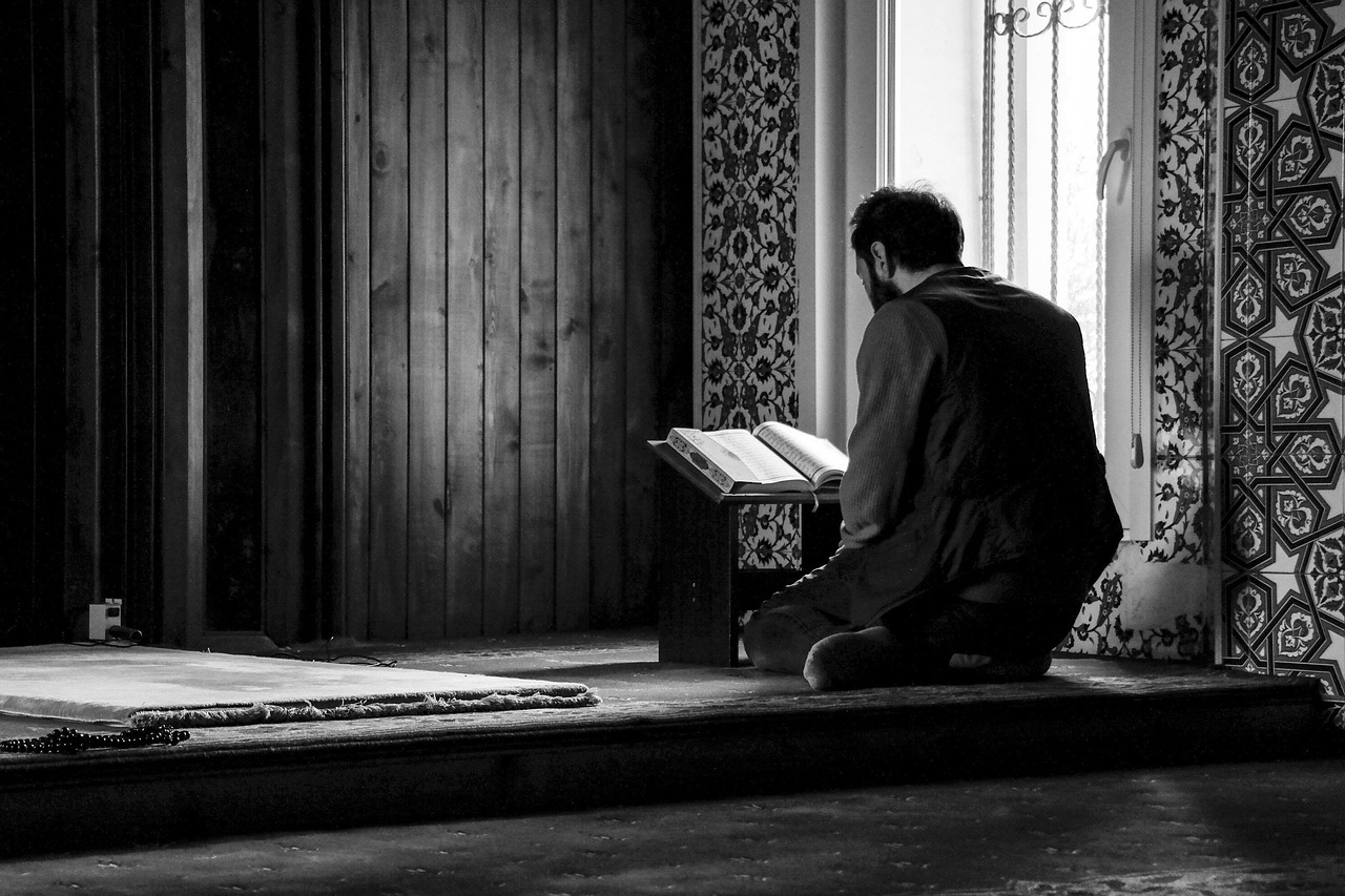 man reciting koran in mosque